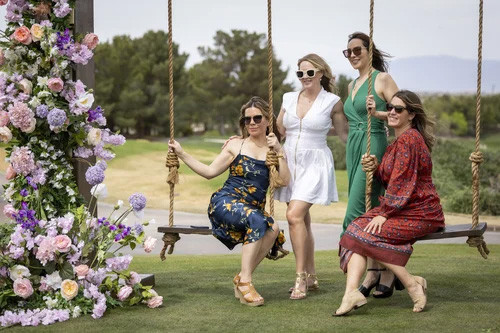 Four women enjoying a garden swing in a park during daytime.
